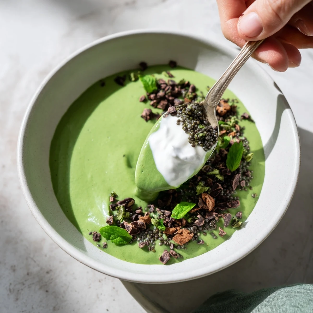 Close-up of a layered Grinch Green Mint Matcha Chia Pudding, topped with berries and chocolate chips.