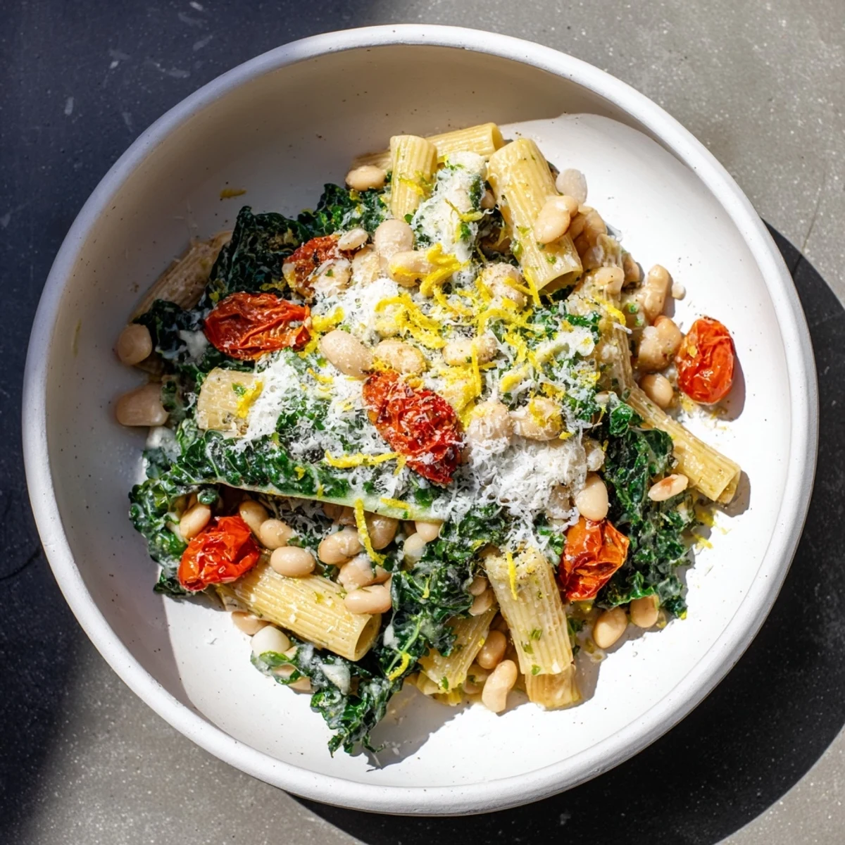 Warm, creamy Healthy Tuscan White Bean & Kale Christmas Pasta, garnished with bright lemon zest and Parmesan.