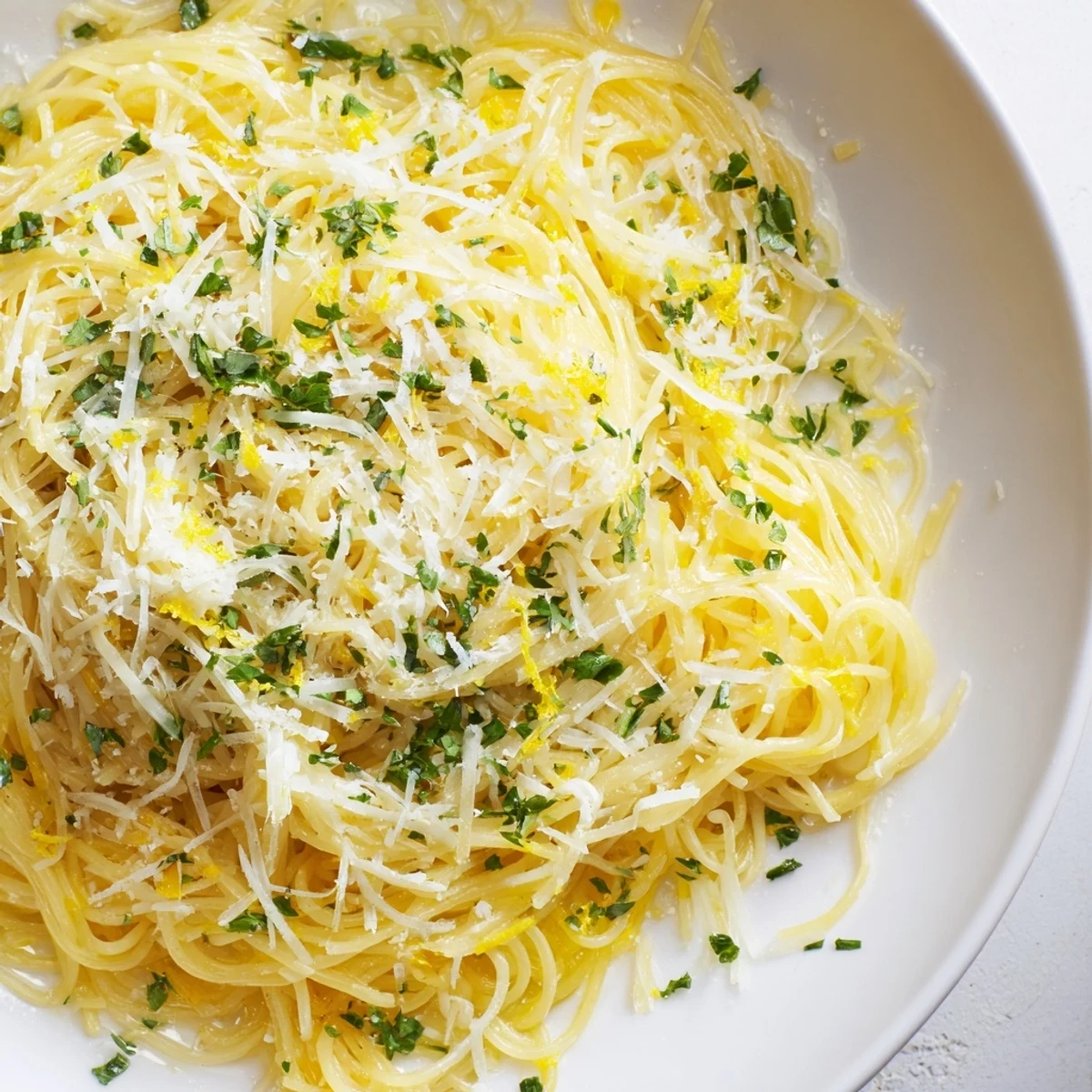 A vibrant photo of Lemon Capellini, showcasing the pasta coated in glossy lemon butter sauce.