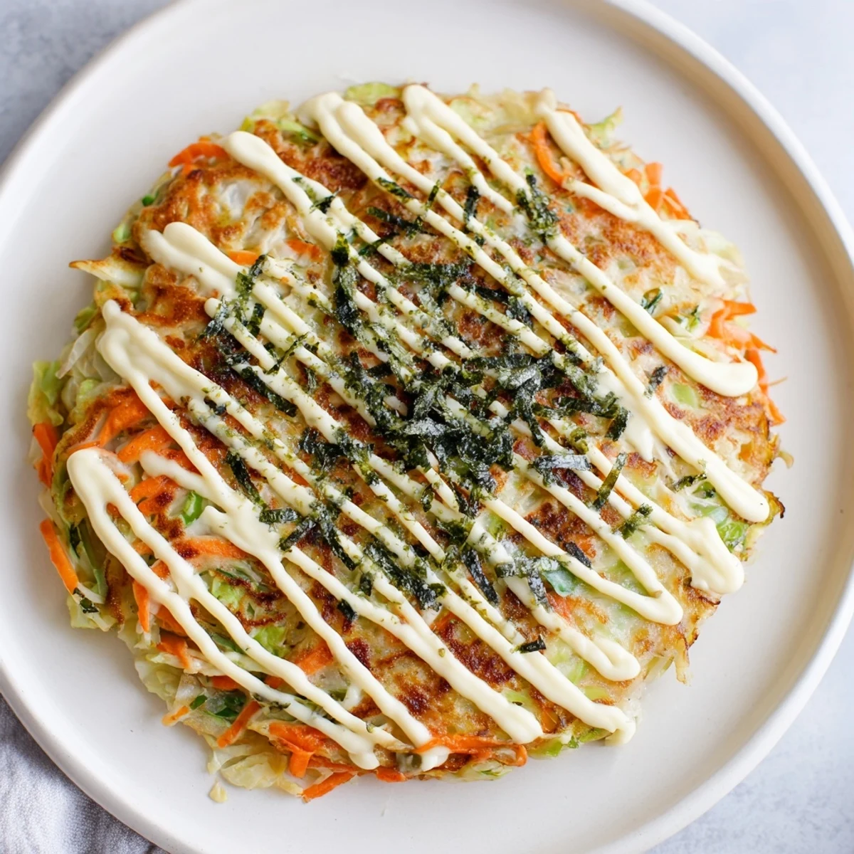 Fluffy Japanese Okonomiyaki Pancakes with crispy bacon edges, drizzled with savory sauce and a zigzag of rich mayonnaise.