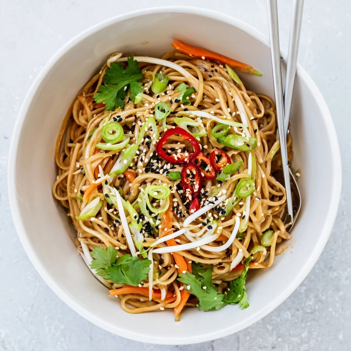 Sizzling Asian Garlic Noodle Bowl in a wok, tossed with julienned carrots and fresh cilantro, steam rising from the hot dish.  
