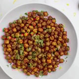 A vibrant bowl of spicy harissa chickpea roast, perfect as a snack with bold North African flavors.