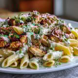 A bowl of Creamy Crockpot Mississippi Chicken Pasta, topped with Parmesan and parsley, served hot and bubbling.