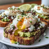 A hearty breakfast toast featuring smashed avocado, a runny poached egg, and crunchy chili oil for bold flavor and texture.