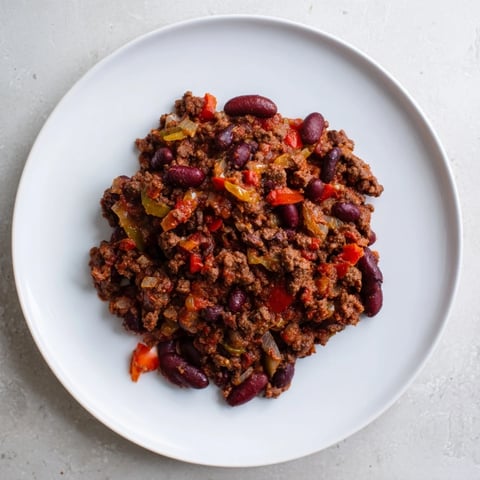 A steaming bowl of Hearty Slow Cooker Beef & Shallot Chili, garnished and ready to serve.