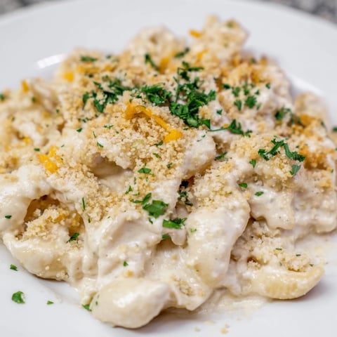 Creamy high-protein mac & cheese with blended cottage cheese, golden top, ready to serve with parsley.