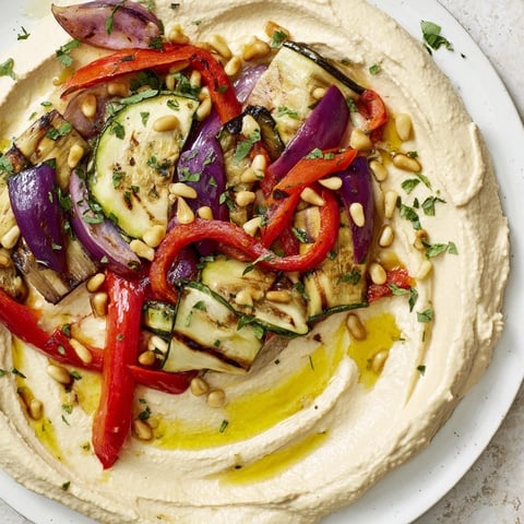 Hummus Roasted Veggies: A vibrant platter of smoky roasted vegetables topping creamy, flavorful hummus.