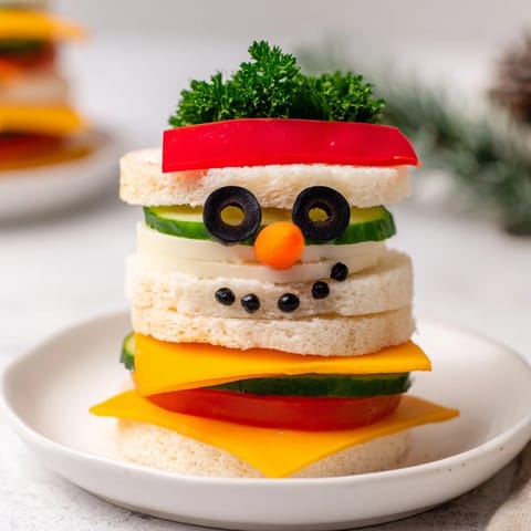 Freshly assembled Snowman Sandwich Stack, featuring colorful veggies and cheese, perfect for a kid-friendly treat.