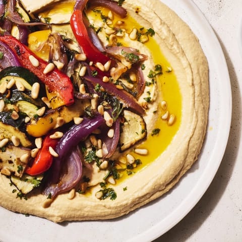 Hummus Roasted Veggies showcased; perfectly charred vegetables with toasted pine nuts atop smooth hummus.