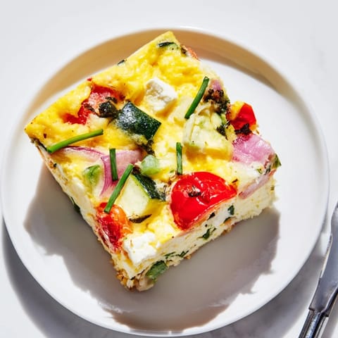 Oven-baked High-Protein Sheet Pan Eggs with Cottage Cheese and Veggies, sliced into golden squares with fresh chives.  