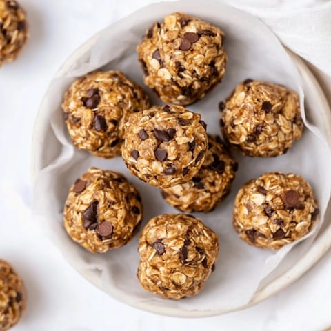 A no-bake Banana Chocolate Chip Energy Ball broken in half showing soft oats and chocolate chips.