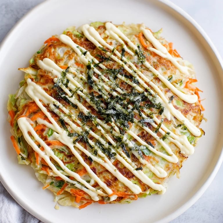 Fluffy Japanese Okonomiyaki Pancakes with crispy bacon edges, drizzled with savory sauce and a zigzag of rich mayonnaise.