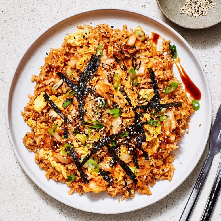 Garnished with sliced green onions, toasted sesame seeds, and a crispy fried egg with a runny yolk on top of the savory Korean dish.  