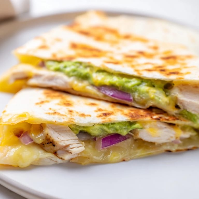 Freshly cooked Chicken Avocado Quesadilla served with lime wedges and cilantro garnish on a wooden board.