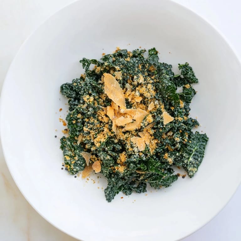 A bowl of Garlic Parmesan Kale Salad with tender olive oil-massaged kale, rich Parmesan dressing, and buttery toasted breadcrumbs for added crunch.