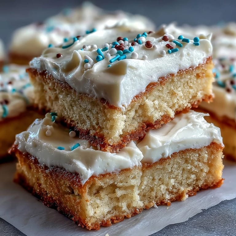 A fork lifts a bite of frosted Almond Flour Sugar Cookie Bars, revealing the soft, chewy almond flour interior.
