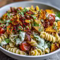 Colorful Taco Pasta Salad with Doritos and Avocado Ranch, topped with crunchy chips and creamy dressing.