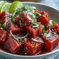 Vibrant Watermelon Cucumber Salad with Tajin and Lime, showcasing juicy cubes of watermelon and crisp cucumber slices, garnished with fresh cilantro and zesty lime wedges.  